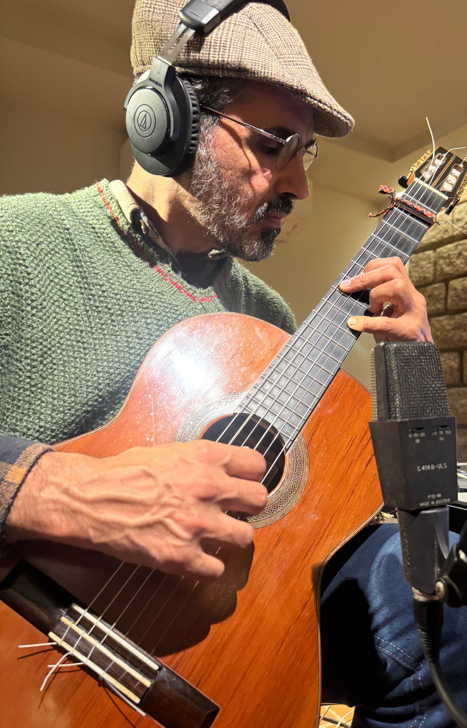 Chico Saraiva tocando violão diante do microfone, no estúdio